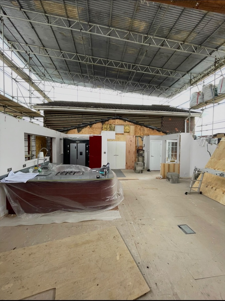 Open plan interior under temporary roof with kitchen island protected during works