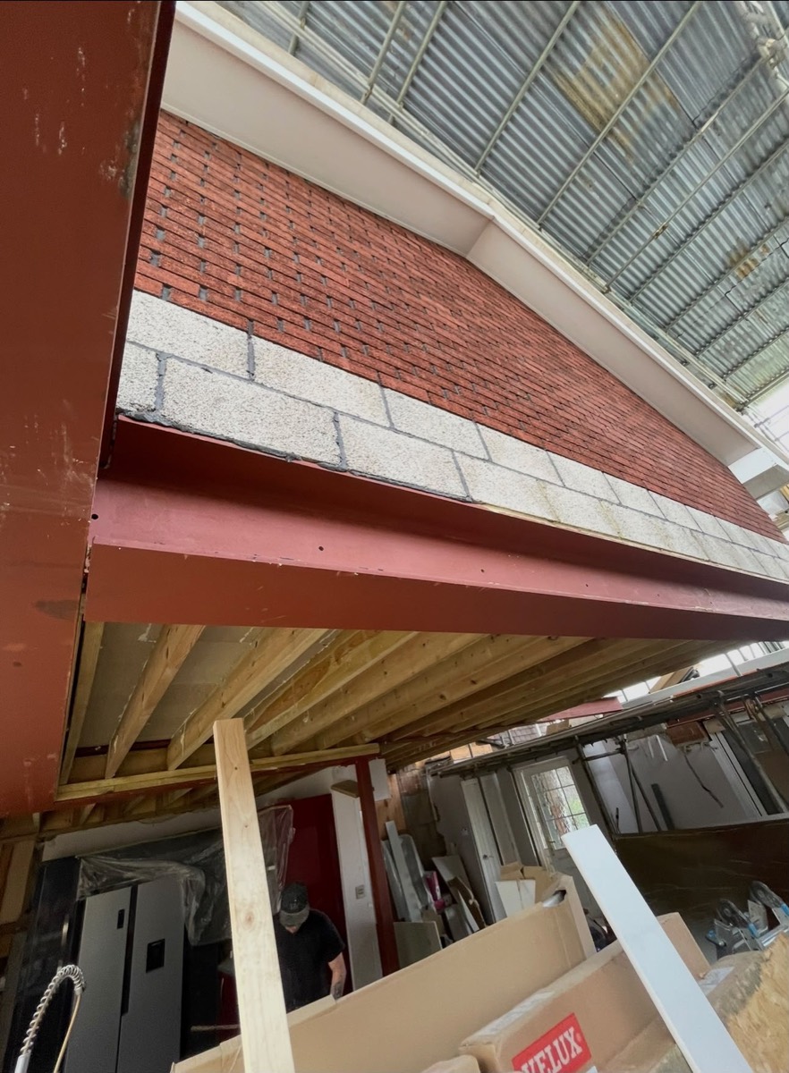 Red structural steel beam supporting new upper floor masonry